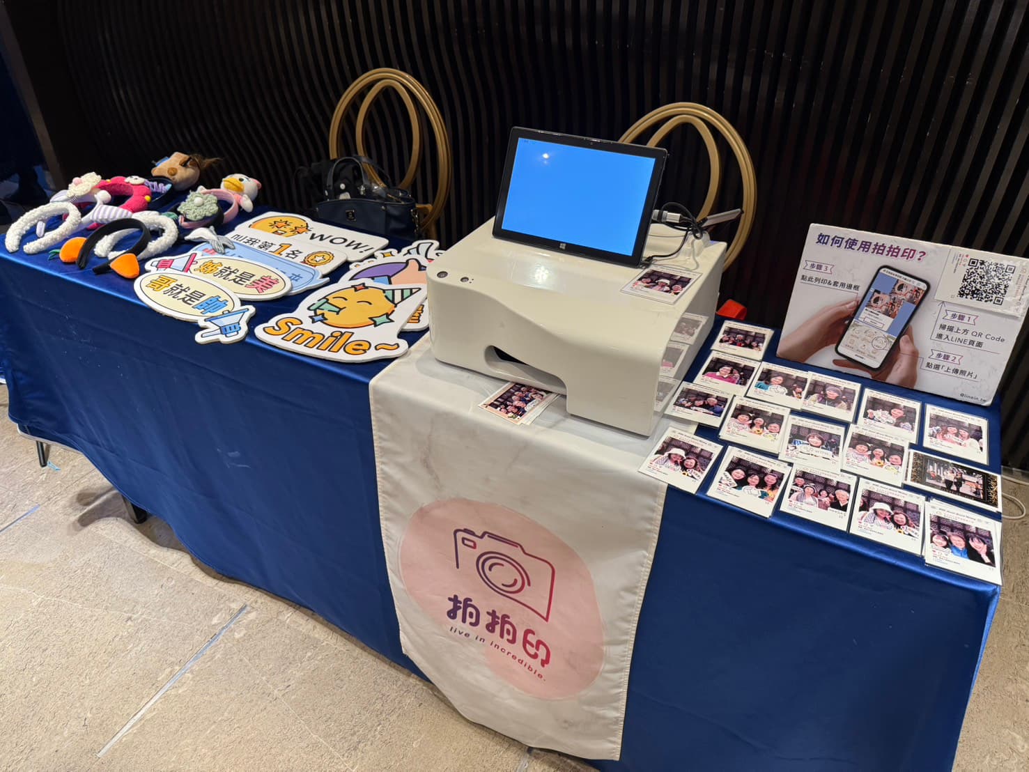 鋪著拍拍印桌旗的長桌上,擺著相片印表機、平板、拍照道具與剛印好的相片